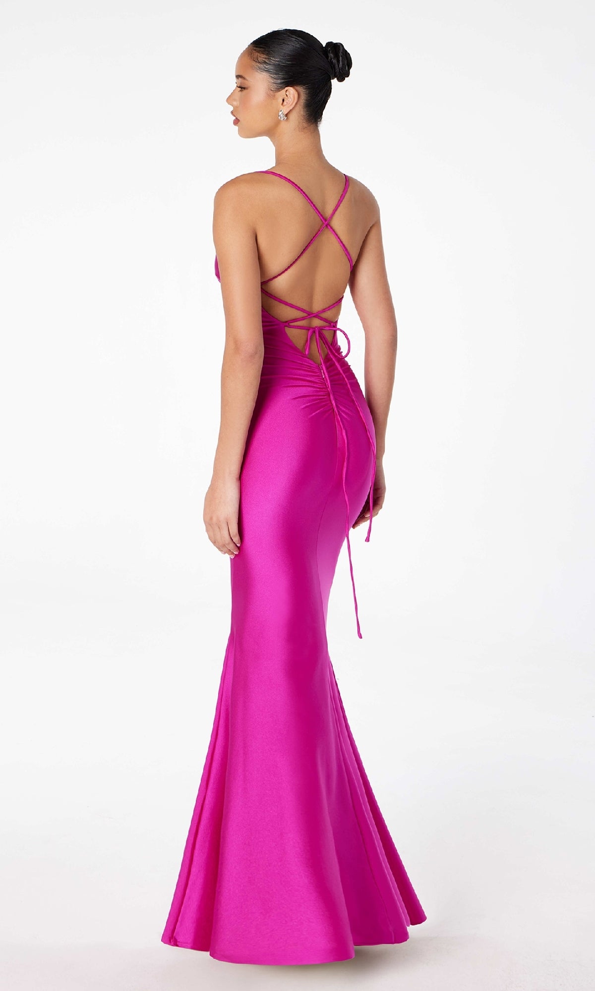 A woman models the Strappy Open-Back Long Prom Dress: Astee T3001, a bright pink floor-length gown featuring thin straps and a crisscross open back, against a plain white background.